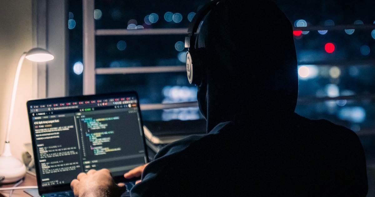 夜間にノートパソコンでコードを確認している開発者